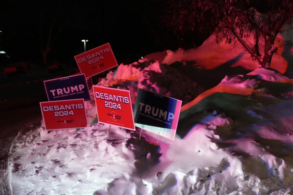 Campaign signs are placed in a snow bank outside a caucus site at Horizon Events Center, in Clive, Iowa, Monday, Jan. 15, 2024. (AP Photo/Andrew Harnik)